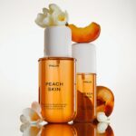 Два флакони PHLUR Peach Skin Hair & Body Fragrance Mist серед персиків і білих квітів