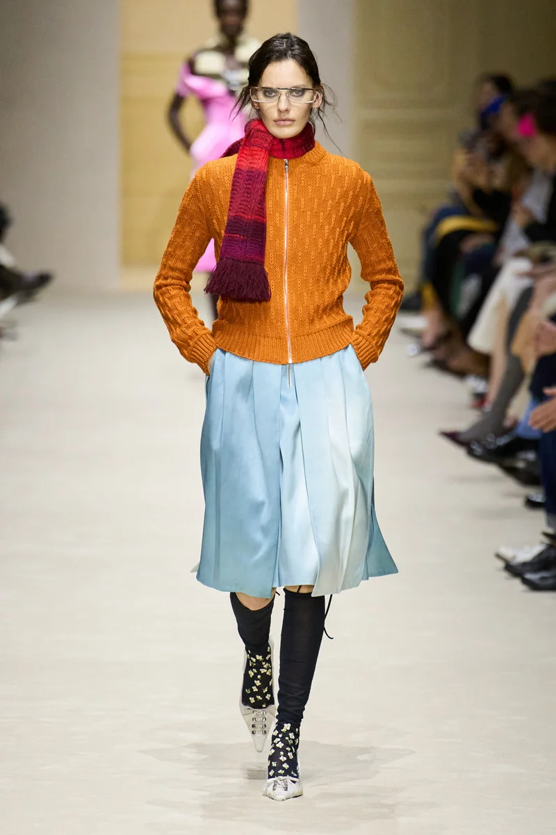 Помаранчевий в'язаний бомбер Prada з блакитною атласною спідницею і червоним шарфом