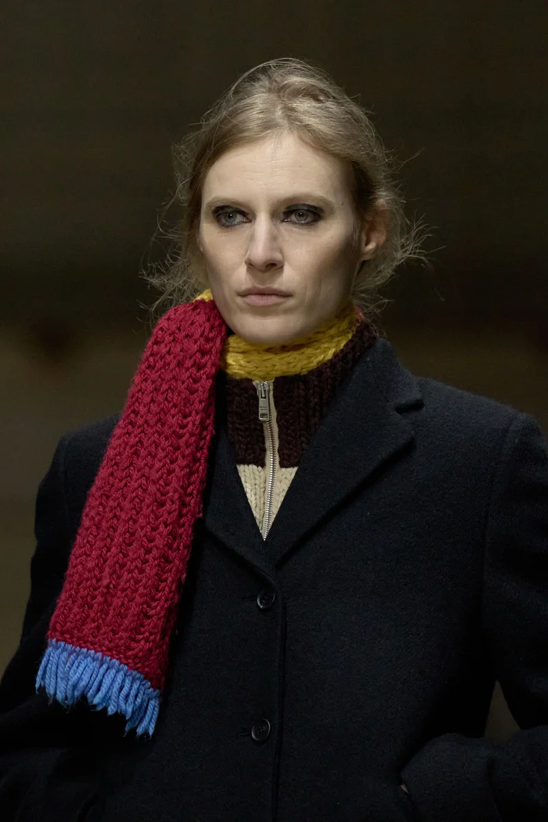 Червоний в'язаний шарф з блакитною бахромою поверх чорного пальта Prada, осінь-зима 2026-2027