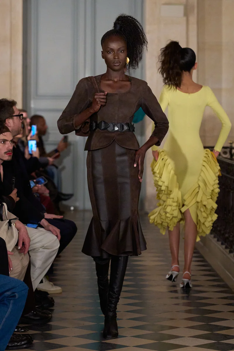 Коричнева шкіряна куртка Jacquemus з округлим вирізом, спідниця в тон, чорний пояс і чорні чоботи