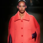 Кораловий вовняний кейп-пальто Balenciaga з відкладним коміром і прорізами для рук, фіолетові шкіряні рукавички, осінь-зима 2026-2027